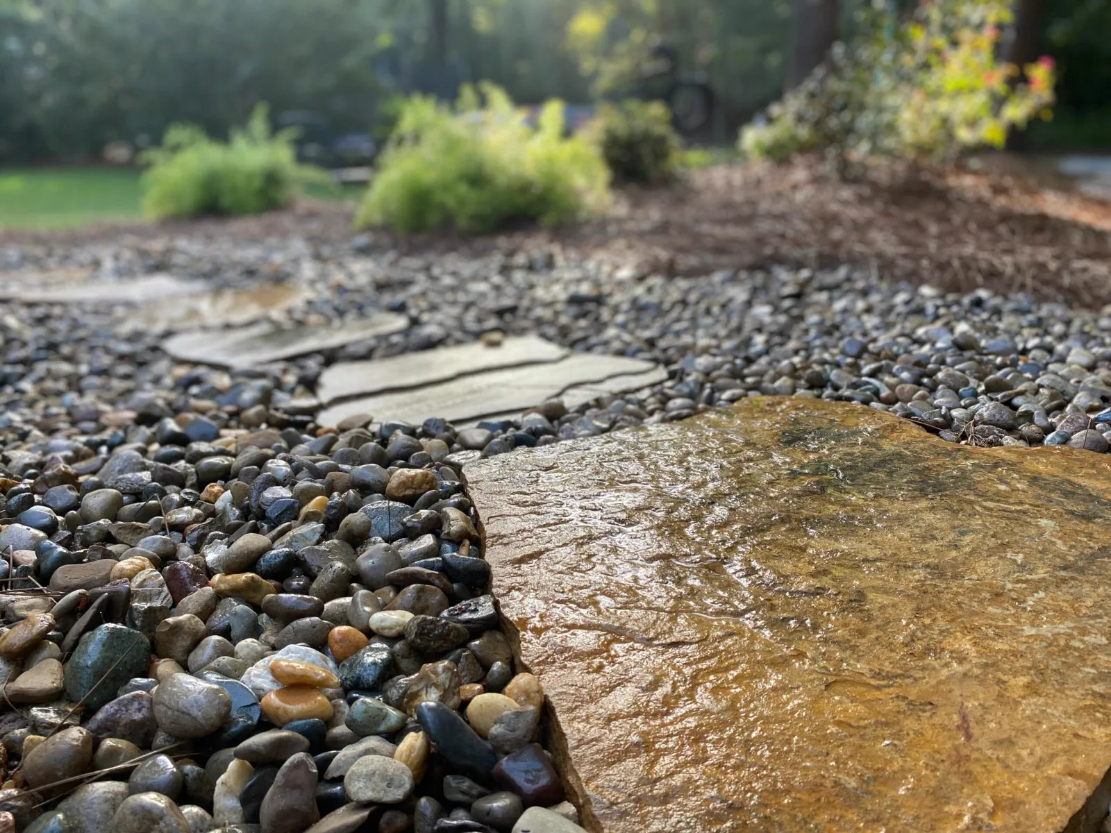 Dry creek bed of river rock set into a planted swale, built to carry runoff away from a house