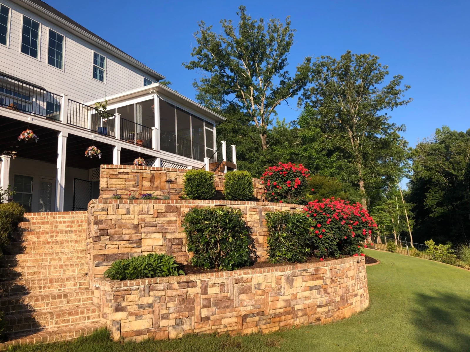 Stacked stone retaining wall with layered shrub and flower beds at a home in Evans, Georgia
