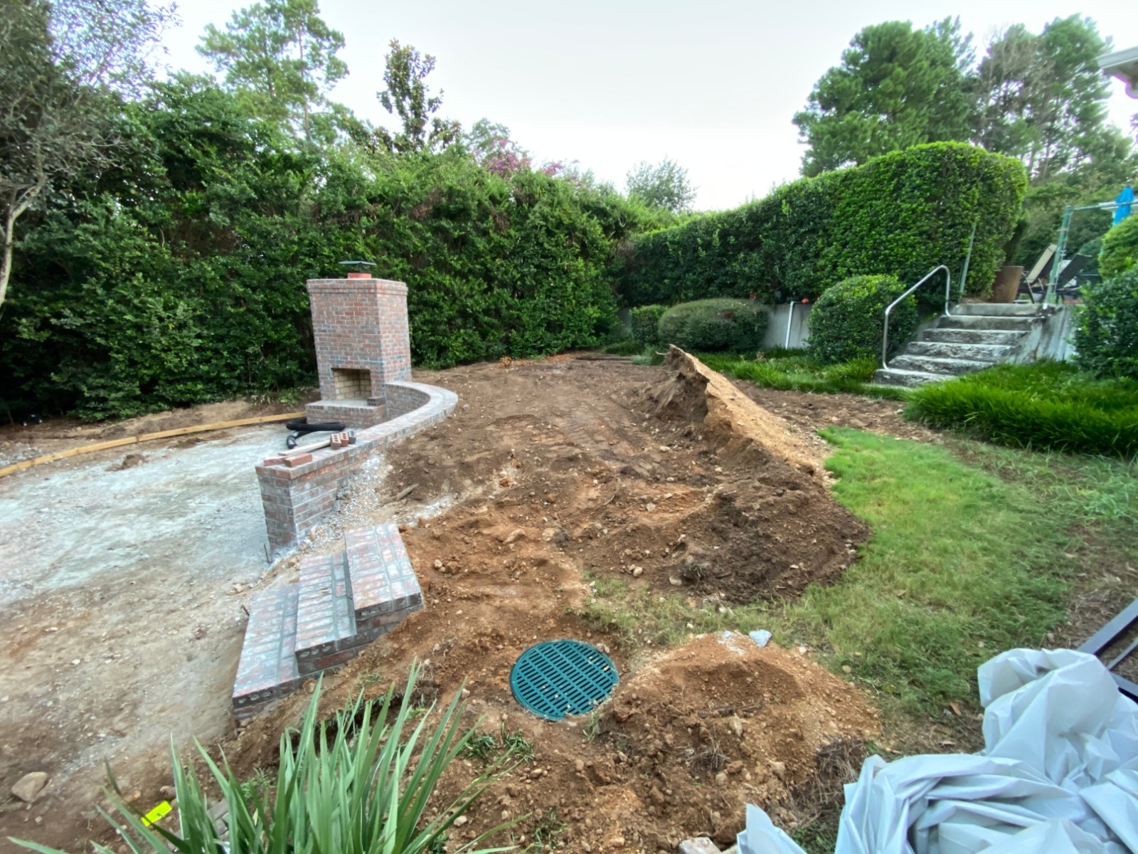 Brick outdoor fireplace under construction with a drainage basin set into the grade